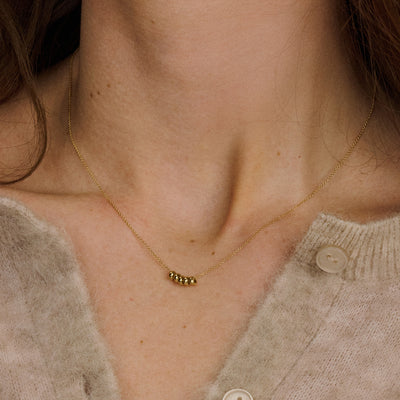 Delicate ketting met vijf kleine ringvormige hangers in glanzend 14k goud, subtiel gedragen bij lichte trui.