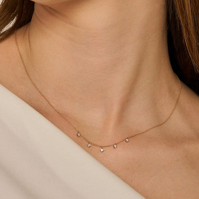 Fijne ketting van 14k goud met vijf kleine zirkonia bedels subtiel verspreid.