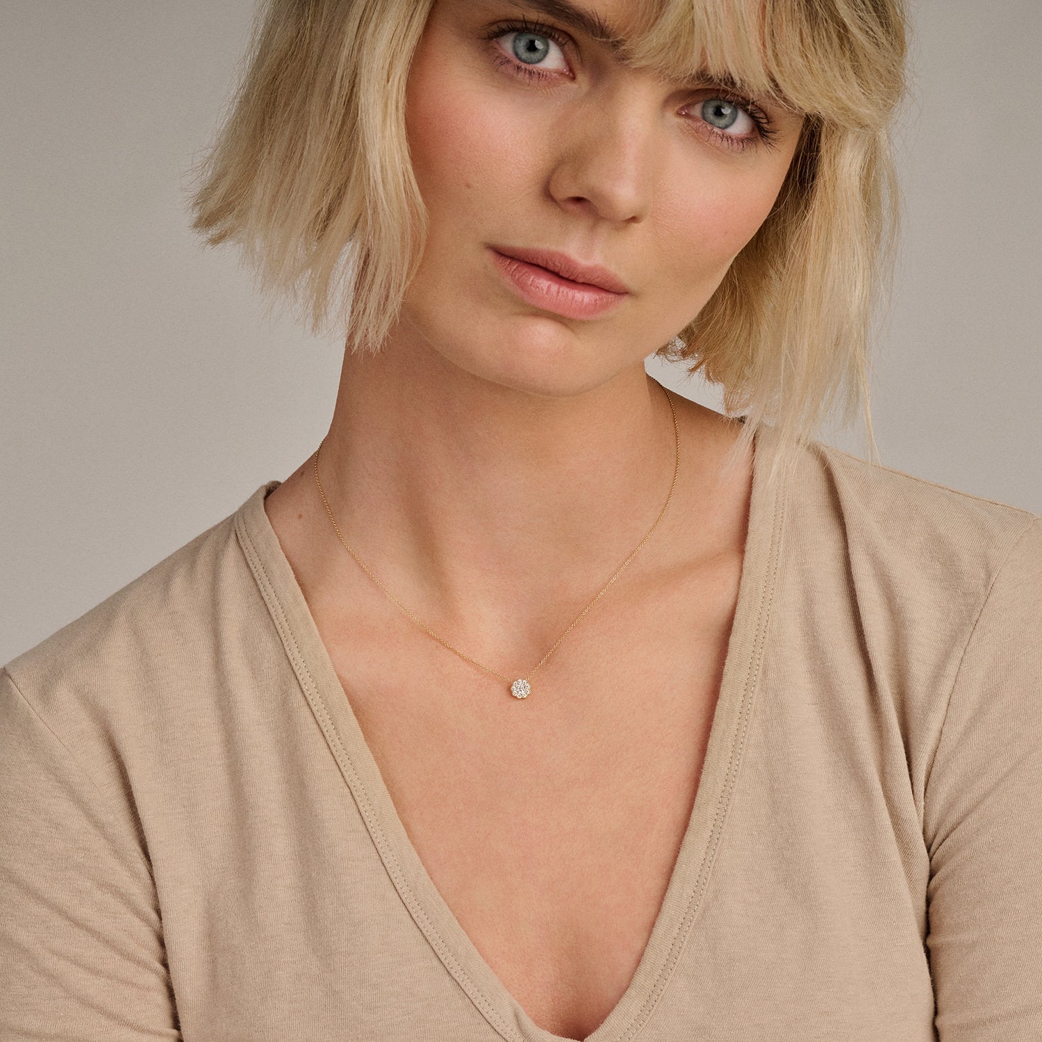 Zilverkleurige ketting met kleine zirkonia hanger in 14k goud bij beige top.