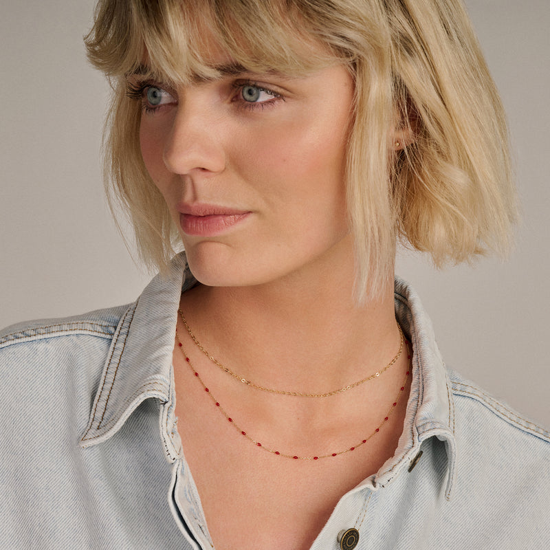 Fijn 14k goud kettinkje met kleine schakels gedragen met roodachtige kralen ketting.