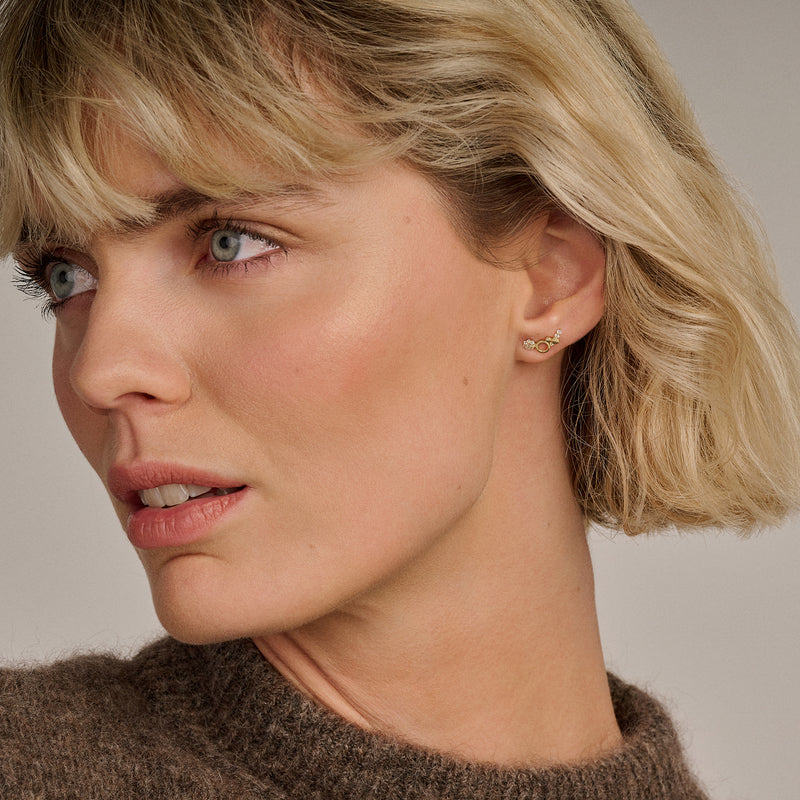 14k goud oorknopjes met kleine glinsterende zirkonia studs gedragen aan oor.