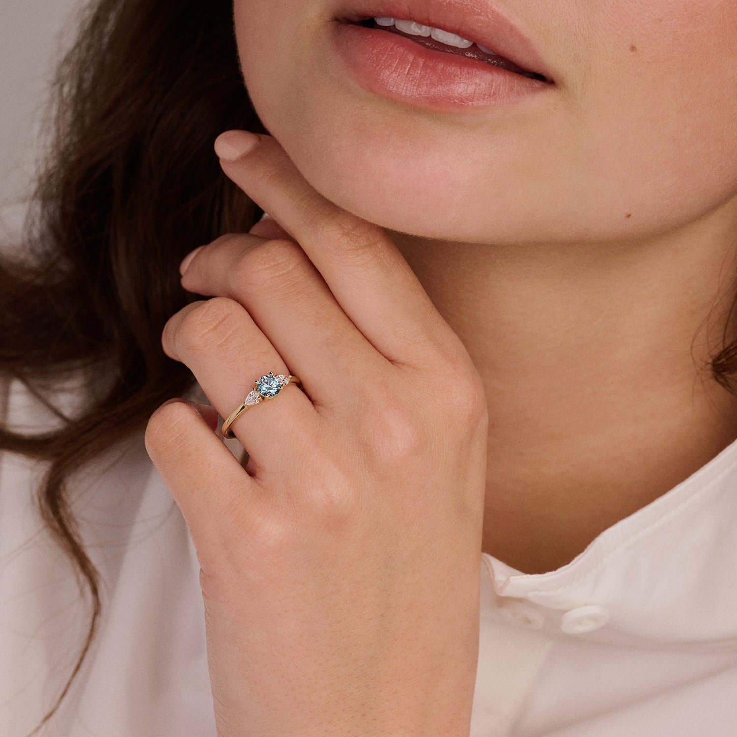 Bague en or jaune 14 carats Bague sertie de Diamant de synthèse et d'un diamant bleu, portée au doigt.