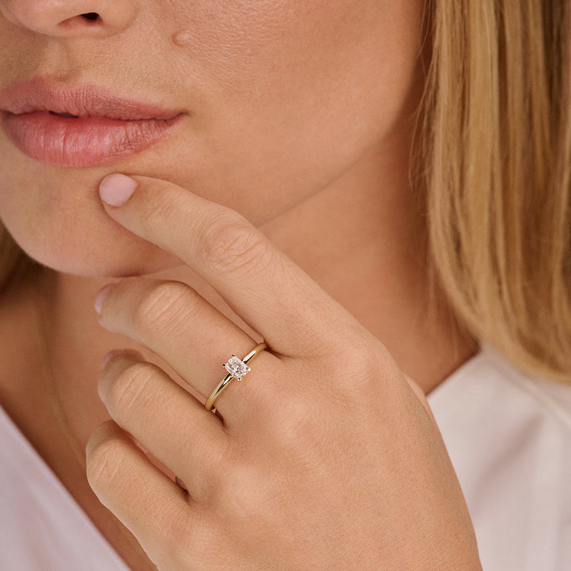 Bague en or jaune 14 carats Bague avec une pierre ovale Diamant de synthèse, portée au doigt.