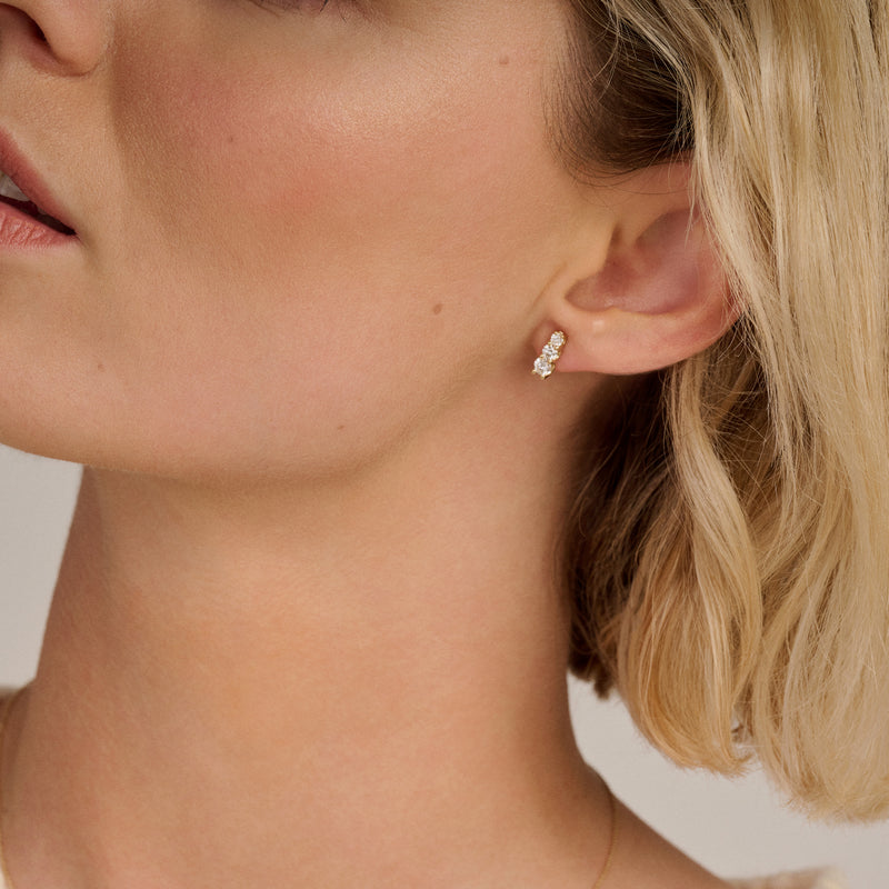 14k goud oorstekers met drie kleine lab diamanten in rij aan oorlel.