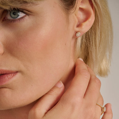 14k goud oorsteker met ronde lab diamond in close-up op oor van vrouw.