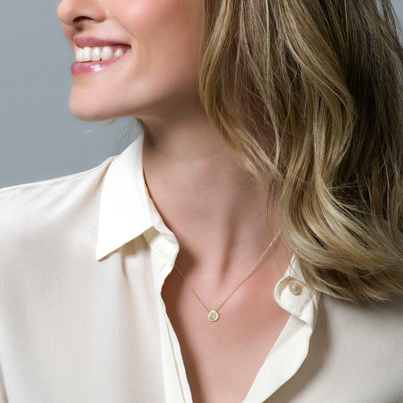 Bicolor ketting met 14k geel en wit goud en kleine zirconia hanger, gedragen bij lichte blouse.